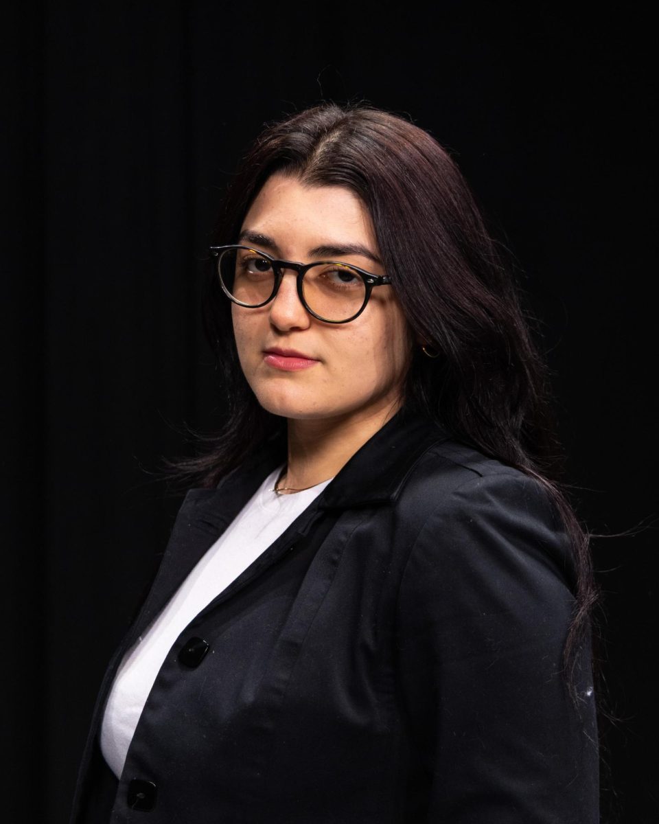 A person standing in front of a black background.